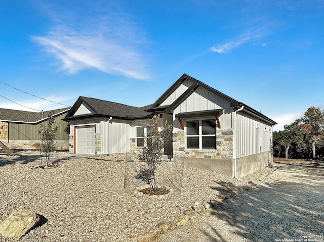 1229 Marlys, Canyon Lake, TX 78133 - view of front facade with board and batten siding, a garage, and stone siding