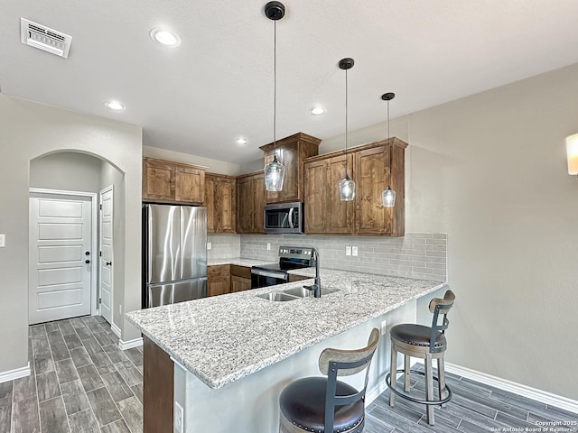1229 Marlys, Canyon Lake, TX 78133 - kitchen with appliances with stainless steel finishes, baseboards, a peninsula, wood tiled floors, and arched walkways