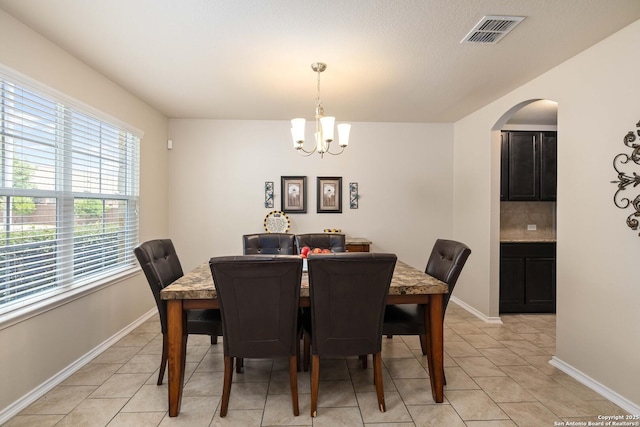 12162 Remilly Way, Schertz, TX 78154 - dining area featuring light tile patterned floors, a chandelier, arched walkways, and baseboards
