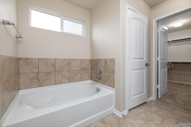 12162 Remilly Way, Schertz, TX 78154 - bathroom with a bath, a walk in closet, baseboards, and tile patterned flooring