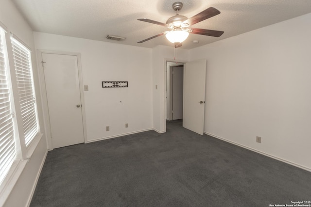 13043 Woller Crk, San Antonio, TX 78249 - spare room with dark carpet, a ceiling fan, and a textured ceiling