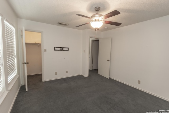 13043 Woller Crk, San Antonio, TX 78249 - unfurnished bedroom with dark colored carpet, a spacious closet, a textured ceiling, a ceiling fan, and a closet