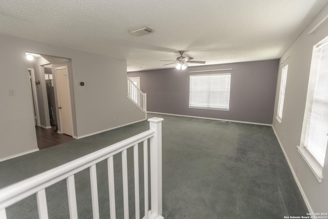 13043 Woller Crk, San Antonio, TX 78249 - spare room with stairs, ceiling fan, a textured ceiling, baseboards, and dark carpet