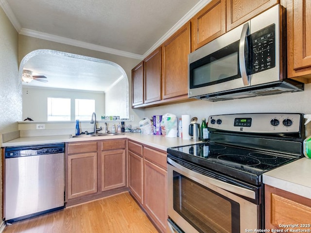 4622 Stallion Cv, San Antonio, TX 78244 - kitchen featuring appliances with stainless steel finishes, a sink, crown molding, light wood-style floors, and light countertops