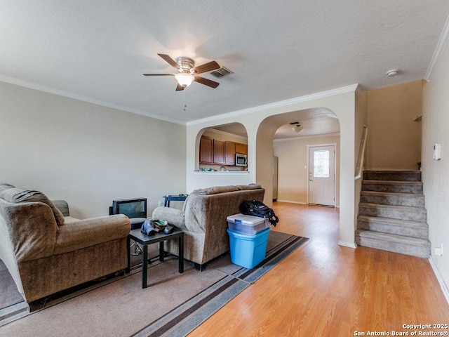 4622 Stallion Cv, San Antonio, TX 78244 - living room with a ceiling fan, crown molding, light wood-style floors, arched walkways, and baseboards