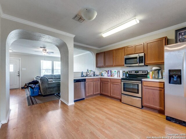 4622 Stallion Cv, San Antonio, TX 78244 - kitchen featuring appliances with stainless steel finishes, arched walkways, light wood finished floors, light countertops, and crown molding