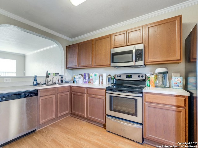 4622 Stallion Cv, San Antonio, TX 78244 - kitchen featuring appliances with stainless steel finishes, light countertops, light wood finished floors, a sink, and crown molding