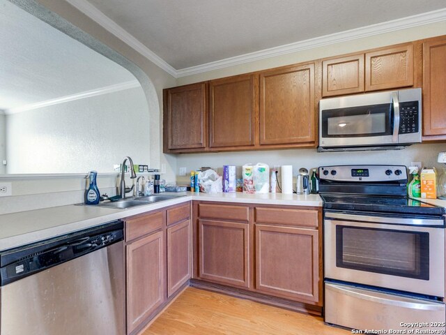 4622 Stallion Cv, San Antonio, TX 78244 - kitchen with stainless steel appliances, a sink, ornamental molding, light countertops, and light wood-style floors