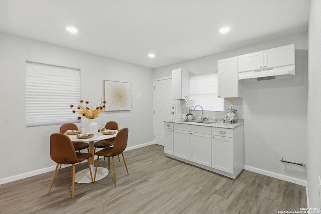 315 Morrill, San Antonio, TX 78214 - kitchen featuring a sink, under cabinet range hood, light wood-style flooring, white cabinets, and baseboards