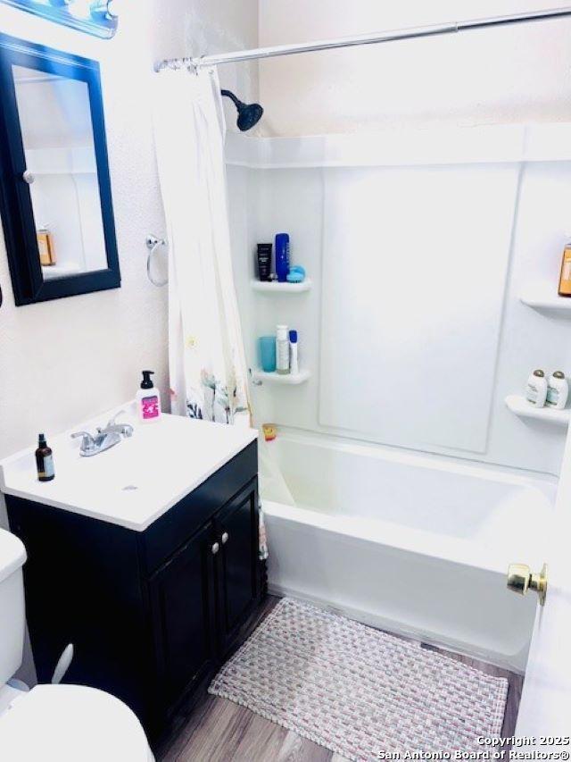 703 Mcdougal, San Antonio, TX 78223 - bathroom with toilet, vanity, shower / tub combo, and wood finished floors