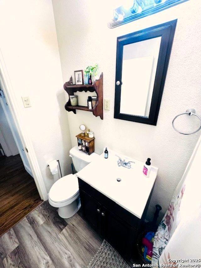 703 Mcdougal, San Antonio, TX 78223 - bathroom with wood finished floors, toilet, and vanity