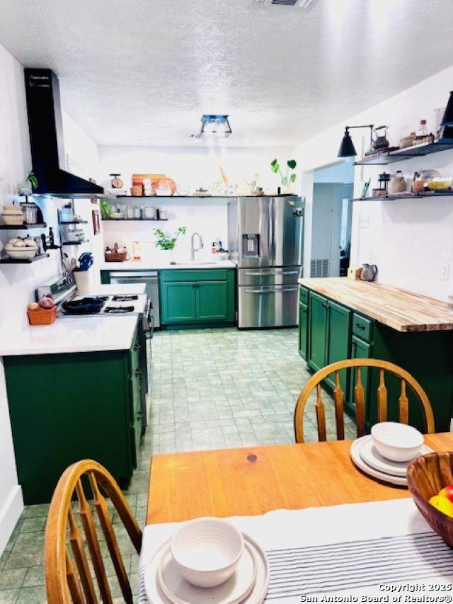 703 Mcdougal, San Antonio, TX 78223 - kitchen featuring green cabinets, open shelves, stainless steel fridge with ice dispenser, wall chimney exhaust hood, and a sink