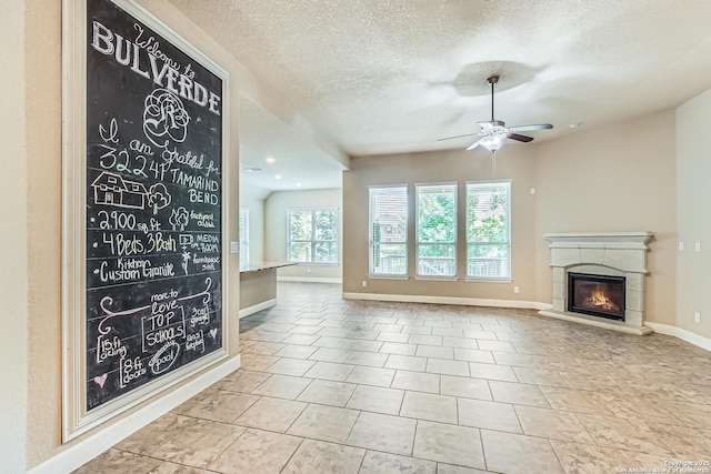 32241 Tamarind, Bulverde, TX 78163 - unfurnished living room with a textured ceiling, a ceiling fan, baseboards, a glass covered fireplace, and tile patterned floors