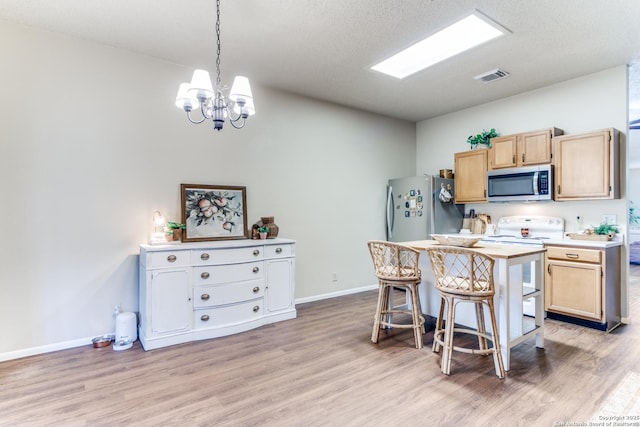 9515 Wicklow, San Antonio, TX 78250 - kitchen featuring stainless steel microwave, freestanding refrigerator, white electric range, a chandelier, and light wood-style floors