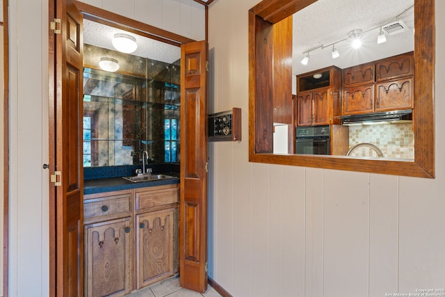 2822 Low Oak, San Antonio, TX 78232 - indoor wet bar with black oven, under cabinet range hood, a textured ceiling, and light tile patterned flooring