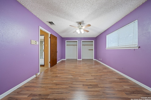2822 Low Oak, San Antonio, TX 78232 - unfurnished bedroom featuring wood finished floors, a textured ceiling, multiple closets, a ceiling fan, and baseboards