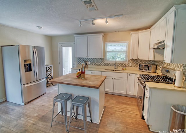522 Rector, San Antonio, TX 78216 - kitchen with appliances with stainless steel finishes, a sink, butcher block countertops, under cabinet range hood, and a kitchen breakfast bar