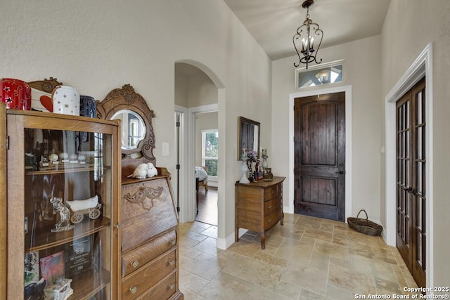 108 Westfield Ln, Vernia, TX 78121 - entryway featuring arched walkways, stone tile floors, a chandelier, a high ceiling, and baseboards