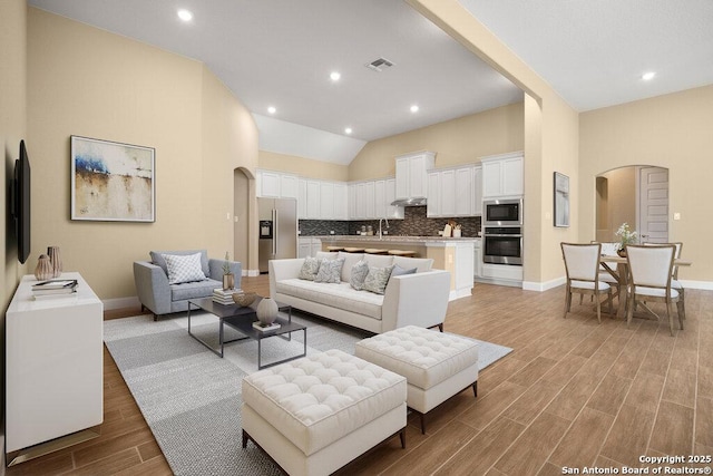 147 Bedingfeld, Shavano Park, TX 78231 - living room with arched walkways, light wood-style flooring, lofted ceiling, baseboards, and recessed lighting