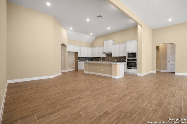 147 Bedingfeld, Shavano Park, TX 78231 - kitchen featuring open floor plan, stainless steel microwave, tasteful backsplash, white cabinets, and vaulted ceiling