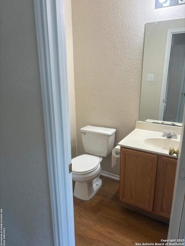 1230 Range Fld, San Antonio, TX 78245 - bathroom with wood finished floors, vanity, toilet, a textured wall, and baseboards
