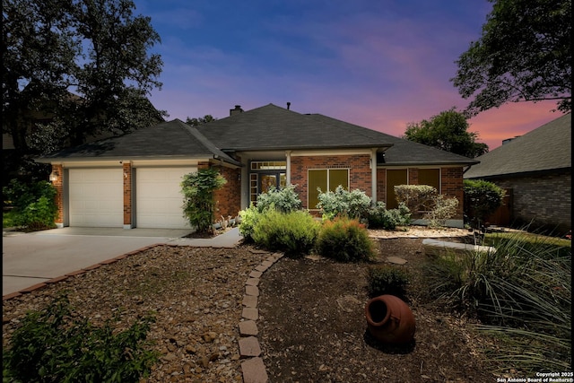5626 Timber Strm, San Antonio, TX 78250 - view of front facade featuring an attached garage, driveway, brick siding, a chimney, and roof with shingles