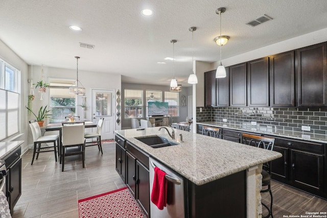 5903 Carriage Cpe, San Antonio, TX 78261 - kitchen featuring stainless steel dishwasher, a sink, tasteful backsplash, a kitchen island with sink, and wood tiled floors