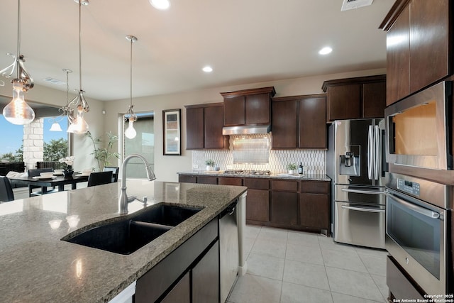 23414 Seven Winds, San Antonio, TX 78258 - kitchen featuring appliances with stainless steel finishes, a sink, decorative backsplash, light tile patterned flooring, and dark stone countertops