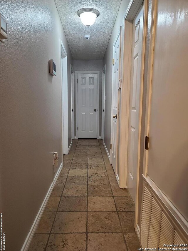 117 Larkspur, Uvalde, TX 78801 - corridor with baseboards, a textured ceiling, and stone tile floors