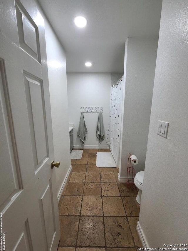 117 Larkspur, Uvalde, TX 78801 - full bath featuring toilet, stone tile flooring, baseboards, and recessed lighting