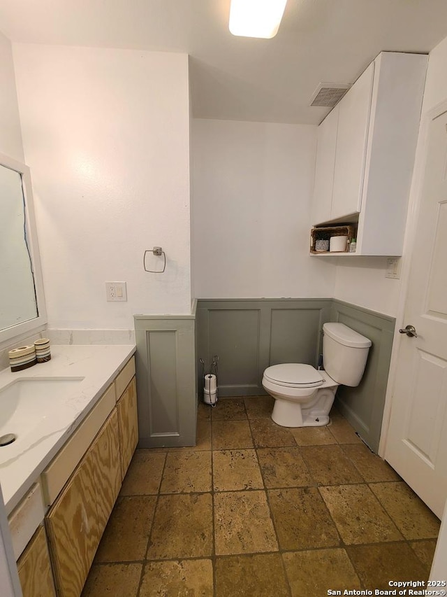 117 Larkspur, Uvalde, TX 78801 - bathroom with stone tile floors, toilet, vanity, and wainscoting