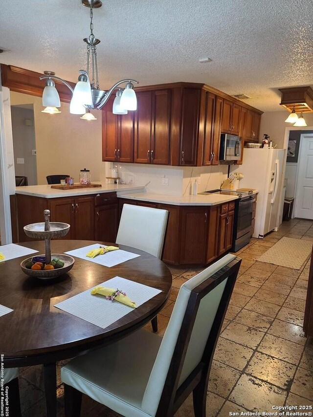 117 Larkspur, Uvalde, TX 78801 - kitchen featuring range with electric cooktop, stainless steel microwave, light countertops, a textured ceiling, and pendant lighting