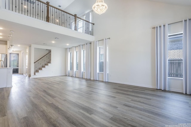 8639 Hedford, San Antonio, TX 78254 - unfurnished living room with a chandelier, plenty of natural light, wood finished floors, a high ceiling, and baseboards