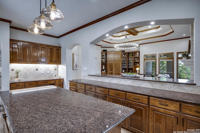112 Legend Holw, Boerne, TX 78006 - kitchen featuring arched walkways, crown molding, backsplash, a center island, and dark stone countertops