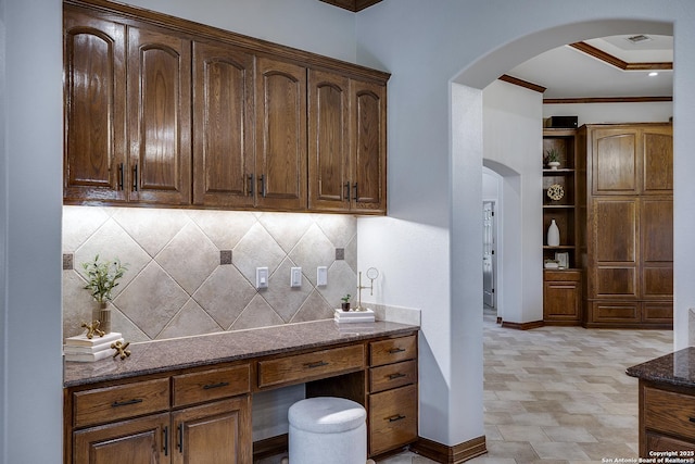 112 Legend Holw, Boerne, TX 78006 - kitchen with arched walkways, dark stone counters, backsplash, ornamental molding, and baseboards