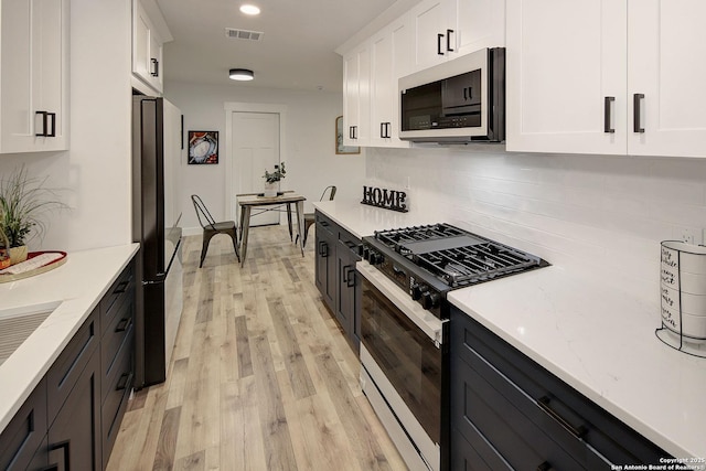 2714 Floral Way, San Antonio, TX 78247 - kitchen with stainless steel microwave, gas range oven, freestanding refrigerator, white cabinets, and tasteful backsplash