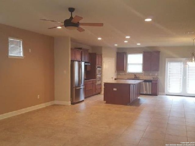 3607 Tea Rose Gln, San Antonio, TX 78259 - kitchen with stainless steel appliances, a ceiling fan, a kitchen island, baseboards, and open floor plan