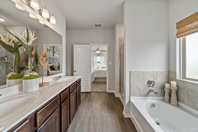 9302 Graze Land Dr, San Antonio, TX 78211 - bathroom featuring wood finished floors, double vanity, a garden tub, and a shower with shower door