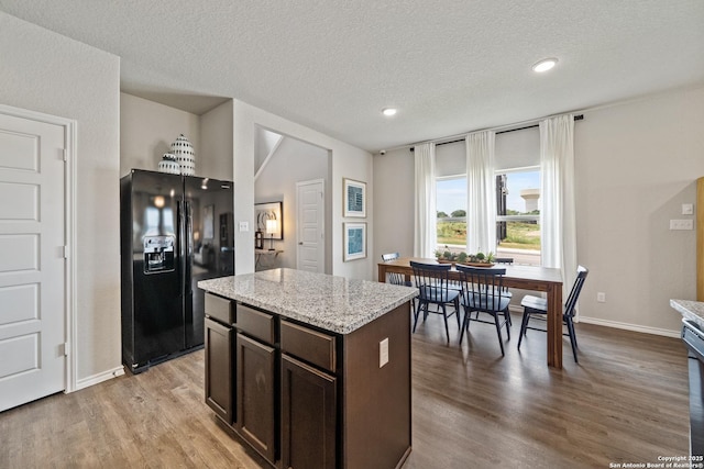 9302 Graze Land Dr, San Antonio, TX 78211 - kitchen featuring black fridge, dark brown cabinets, light wood-type flooring, a center island, and baseboards
