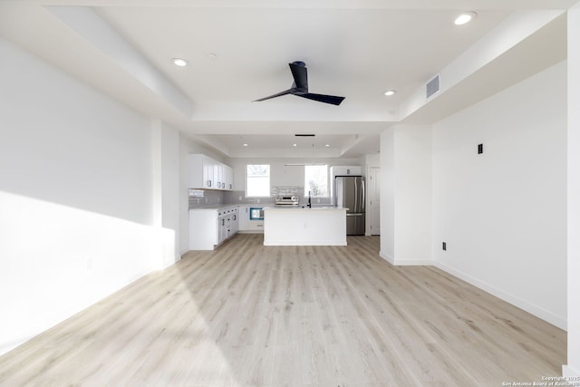 310 S Mesquite St Unit 102, San Antonio, TX 78203 - unfurnished living room featuring a sink, light wood finished floors, recessed lighting, baseboards, and a raised ceiling