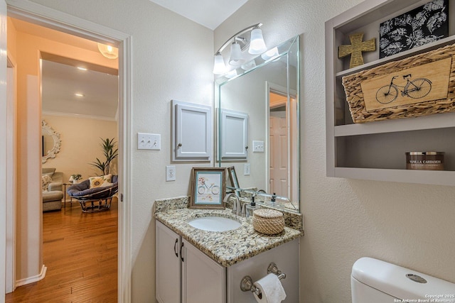9215 Hilltop Xing, San Antonio, TX 78251 - half bathroom with vanity, toilet, wood finished floors, and ornamental molding