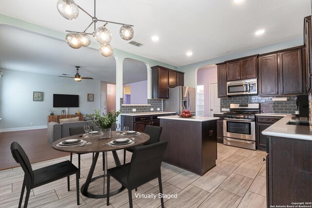 15122 Cinnamon Teal, San Antonio, TX 78253 - kitchen featuring stainless steel appliances, arched walkways, ceiling fan, dark brown cabinets, and decorative backsplash