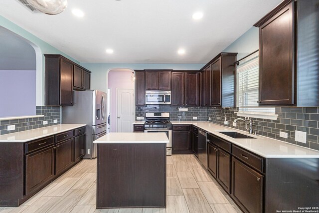 15122 Cinnamon Teal, San Antonio, TX 78253 - kitchen featuring stainless steel appliances, a sink, arched walkways, decorative backsplash, and a kitchen island