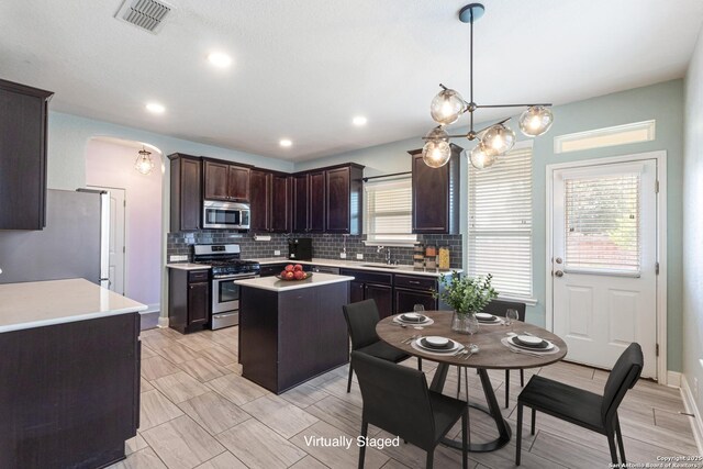 15122 Cinnamon Teal, San Antonio, TX 78253 - kitchen with stainless steel appliances, a sink, dark brown cabinetry, tasteful backsplash, and light countertops
