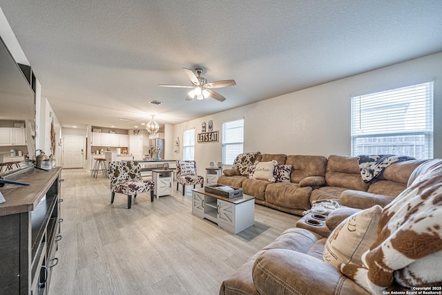 14616 Stable Spgs, Elmendorf, TX 78112 - living area with ceiling fan, light wood-type flooring, a chandelier, and a textured ceiling