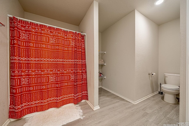 14616 Stable Spgs, Elmendorf, TX 78112 - full bath with wood finished floors, toilet, baseboards, and a shower with shower curtain