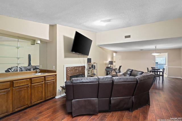 7738 Chambers Rd Unit 1203, San Antonio, TX 78229 - living room with dark wood-style flooring, a fireplace, a textured ceiling, and baseboards