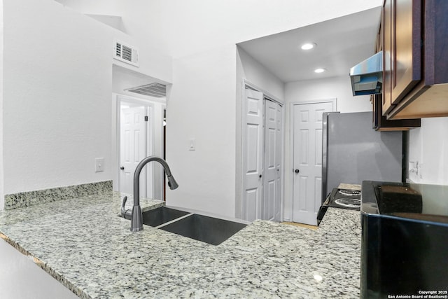 8633 Datapoint Unit 236, San Antonio, TX 78229 - kitchen featuring a sink, range hood, freestanding refrigerator, light stone counters, and a peninsula
