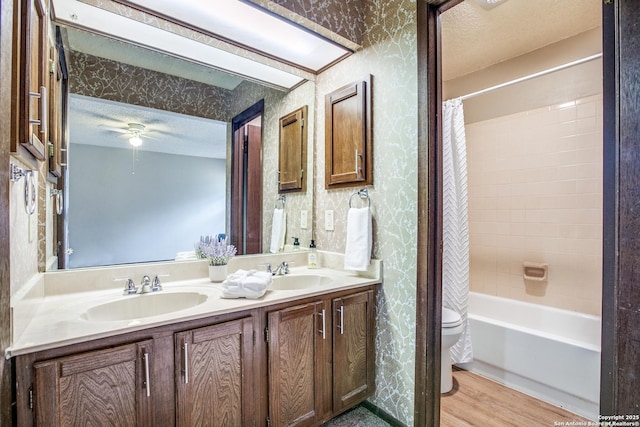 3030 Heidi St, San Antonio, TX 78247 - full bath featuring wallpapered walls, double vanity, toilet, wood finished floors, and shower / bath combination with curtain