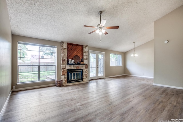 3030 Heidi St, San Antonio, TX 78247 - unfurnished living room with a textured ceiling, ceiling fan, wood finished floors, a stone fireplace, and lofted ceiling